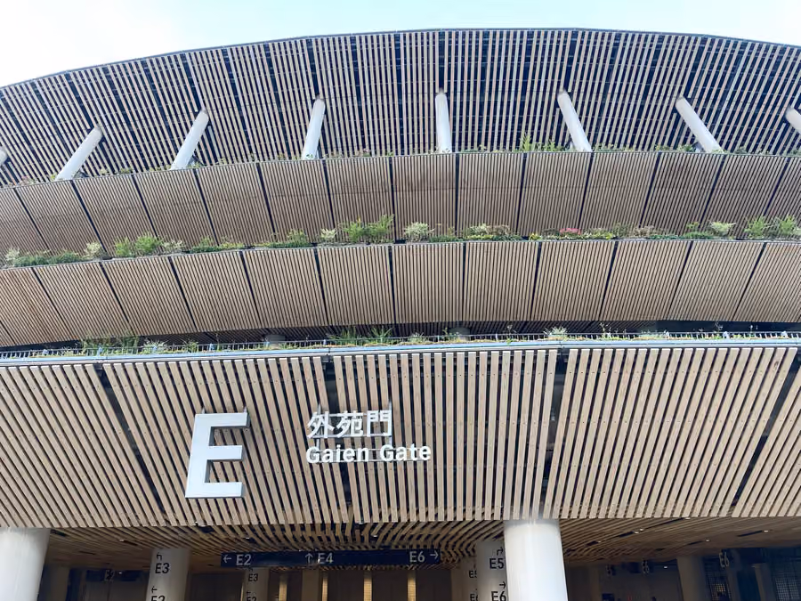 La puerta Gaien del Estadio Nacional. Las paredes están revestidas de madera y hay plantas bajo los aleros.
